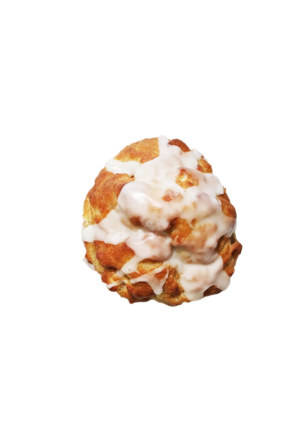 A glazed lemon cookie with lemon zest visible on top, placed on a white surface.