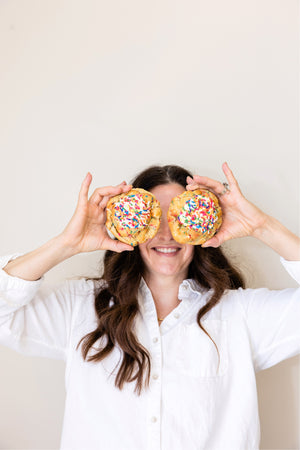 KCookies owner, Christina Jokerst, holding two funfetti cookies in front of her eyes