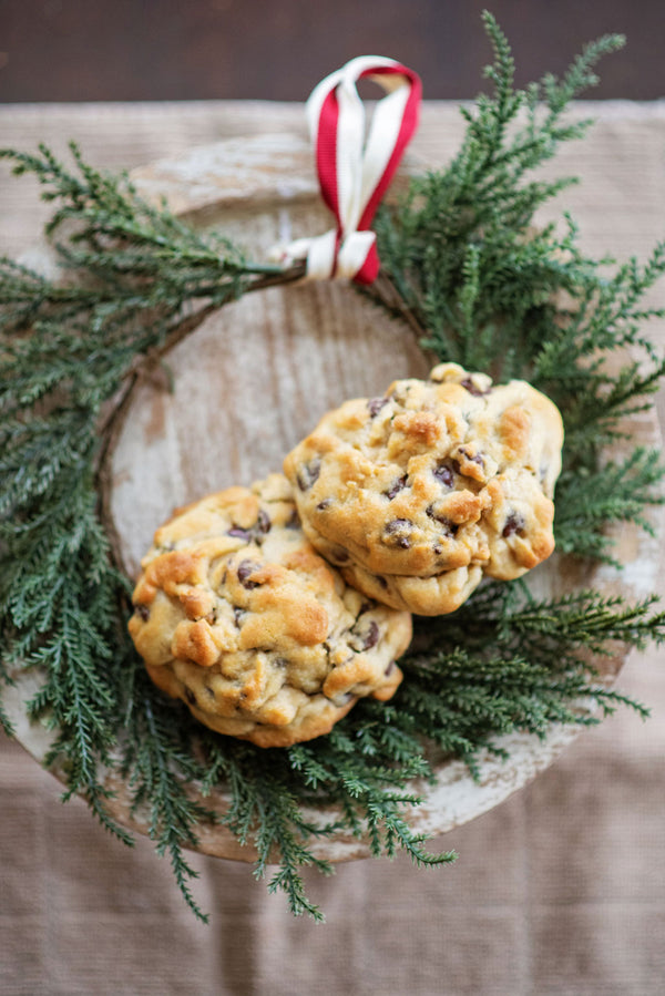 Two of The Duke chocolate chip walnut cookies rested within a green wreath with a red and white ribbon