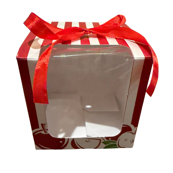 Red and white square box with apple images and a red bow with a cookie inside.  